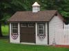 Deluxe Cape Cod 10′ x 14′ • White vinyl siding, brown trim and doors, bark architectural shingles